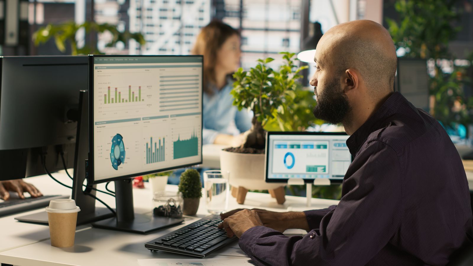 Analista trabalhando diante de monitores com painéis de dados e fluxos automatizados