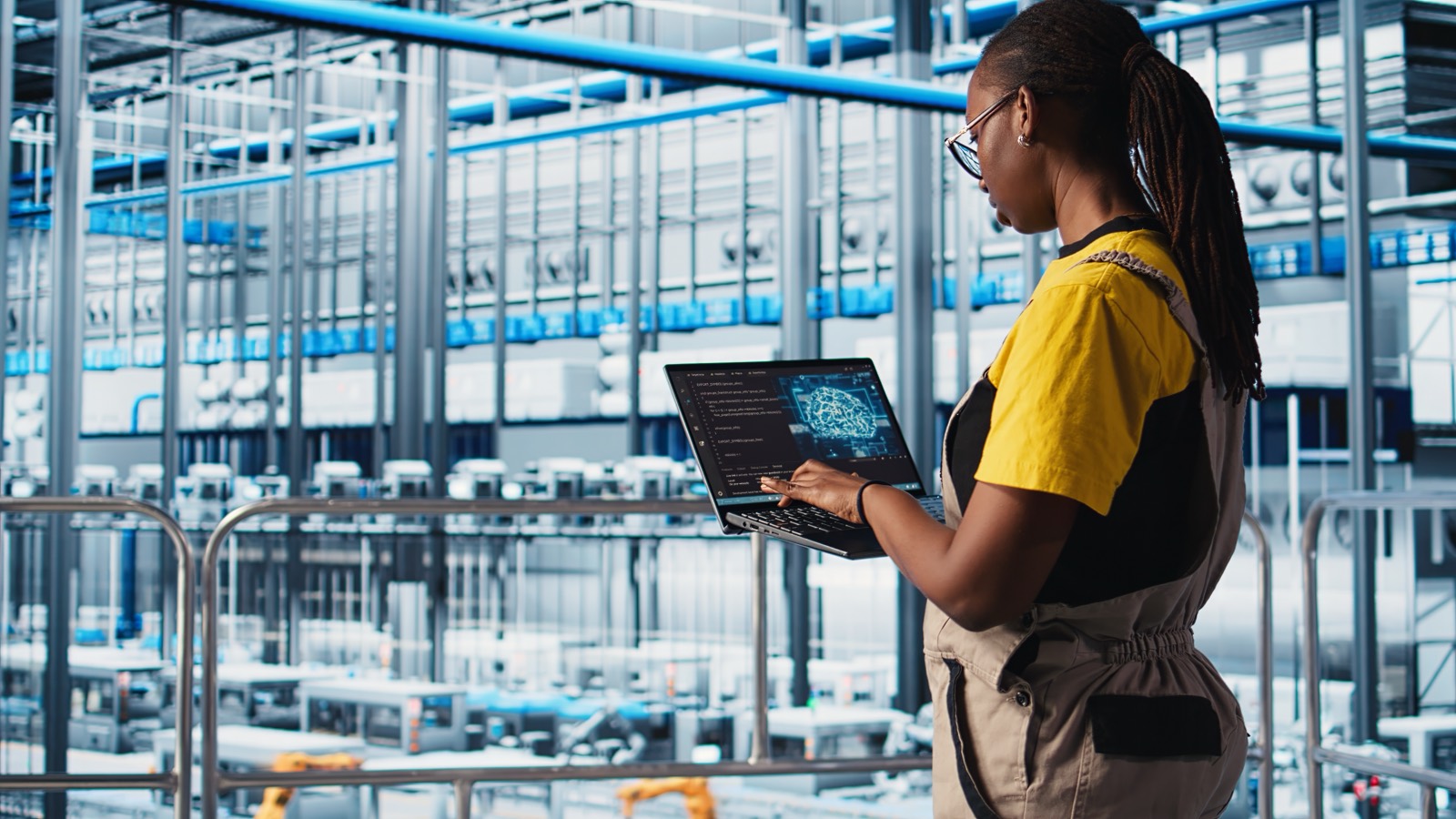 Engenheira acompanhando dados de uma linha de produção automatizada pelo notebook