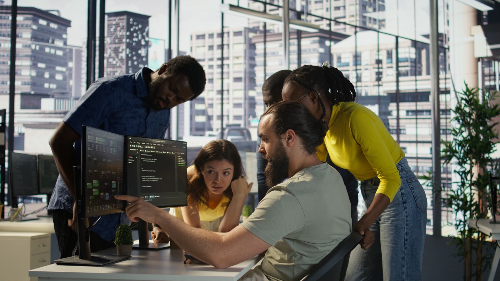 Time de desenvolvimento discutindo uma solução em frente ao monitor com código