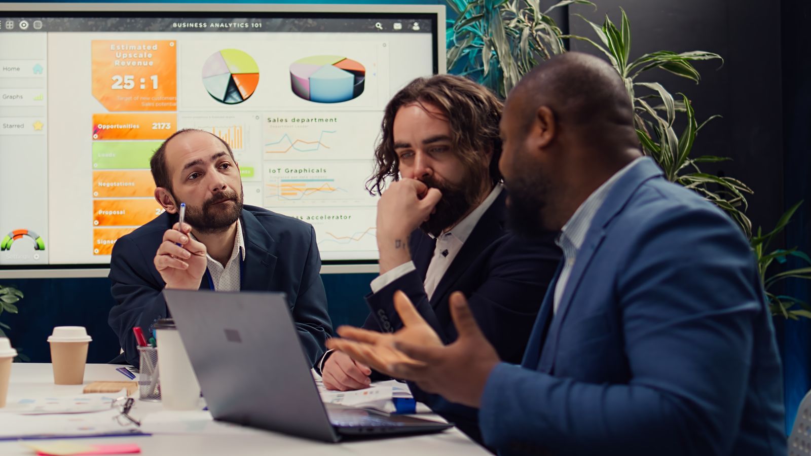 Equipe em reunião discutindo prazos e indicadores de um projeto, com gráficos na tela ao fundo
